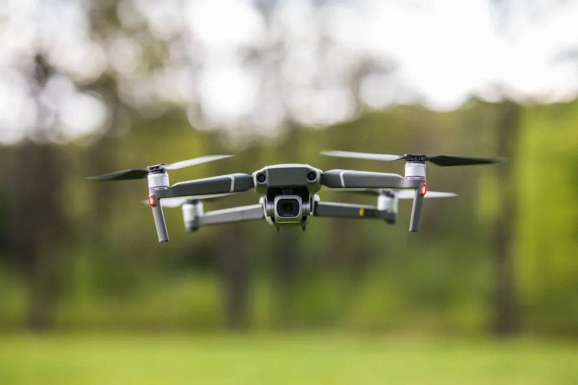 Quadcopter flying on a clear sunny green day background with nice lens flare.